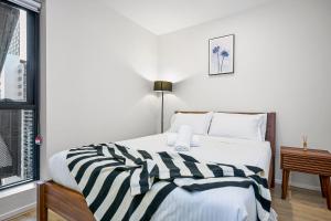 a bedroom with a bed with a black and white striped blanket at Luxe Lonsdale - Your City Retreat in Melbourne in Melbourne
