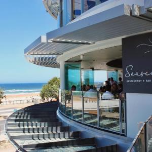 a group of people sitting at a restaurant next to the beach at Cloud Nine Retreat - Luxe 44th Fl Apartment in Gold Coast