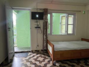 Habitación pequeña con cama y ventana en Mountaintop Guest House, en Bhurtuk