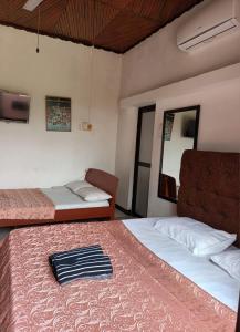 a bedroom with two beds and a chair and a mirror at Chana Bungalow in Ratnapura