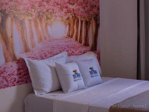 a bed with two pillows with a painting of trees at Hotel e Restaurante Rio Mar in Valença