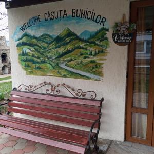 una panchina di fronte a un edificio con un murale di Căsuța Bunicilor a Dorna Cîndrenilor