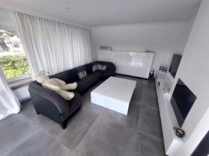 sala de estar con sofá negro y mesa blanca en The White Villa en Blankenberge