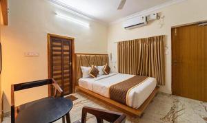 a bedroom with a bed and a desk and a chair at FabHotel Prime AR Phalazzo Resort in Puducherry