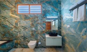 a bathroom with a toilet and a stone wall at FabHotel Prime AR Phalazzo Resort in Puducherry