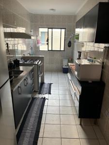 cocina con suelo de baldosa blanca y fregadero en Apartamento beira-mar em Mongaguá, en Mongaguá 2 fotos más