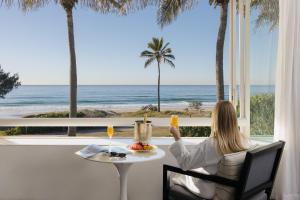 uma mulher sentada numa mesa a olhar para o oceano em Sheraton Grand Mirage Resort Gold Coast em Gold Coast