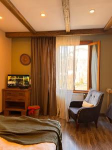 a bedroom with a bed and a chair and a window at Hotel Borjomi Verde in Borjomi