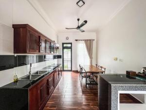a kitchen with wooden cabinets and a dining room at Angkearboss Villa in Kampot