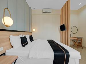 a bedroom with a white bed and a desk at Homi Stay in Solo