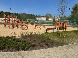 um parque com um parque infantil de madeira com um banco em Witawa 2024 em Gdynia