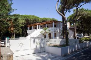 a white house with a white fence and a tree at Villa Consuelo 140 in Rosolina Mare