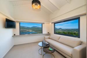 a living room with a couch and two large windows at The "L" Suites & Apartments in Argostoli