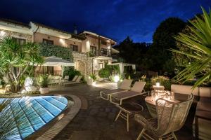 a patio with chairs and a swimming pool at night at Nikoleta Hotel and Villas in Limenas