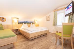 a hotel room with two beds and a television at Self Check-In Pension Schmittental in Zell am See