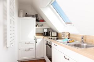 a white kitchen with a sink and a skylight at Fofftein in Juist