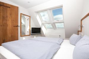two beds in a bedroom with a mirror and a tv at Fofftein in Juist