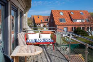 a balcony with a bench and a table and a building at Fofftein in Juist