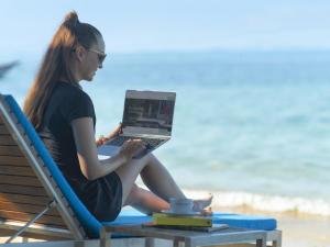 a woman sitting on a beach chair with a laptop at Explorar Koh Phangan - Adults Only Resort and Spa in Haad Rin