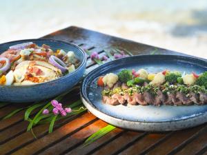 a table with two plates of food and a bowl of vegetables at Explorar Koh Phangan - Adults Only Resort and Spa in Haad Rin
