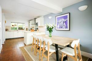 cocina con mesa de madera y armarios blancos en Roseberry Cottage - Lower Mill Estate, en Somerford Keynes
