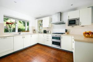 a kitchen with white cabinets and a wooden floor at Roseberry Cottage - Lower Mill Estate in Somerford Keynes