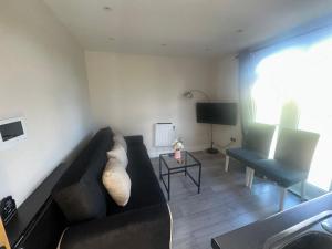 ein Wohnzimmer mit einem schwarzen Sofa und einem TV in der Unterkunft Cheviot loft in London