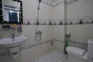 ein Bad mit einer Dusche, einem Waschbecken und einem WC in der Unterkunft Hotel Trâm Anh in Nhơn Trạch