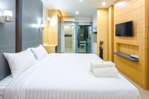 a bedroom with a large white bed and a tv at Phoomjai Service Apartment in Ban Klang