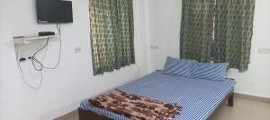 a small bedroom with a bed and a tv at Sandhya Guest House in Digha