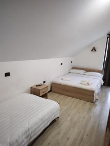 ボルシャにあるVila Puiu Borsa MMの白い壁とウッドフロアの客室で、ベッド2台が備わります。