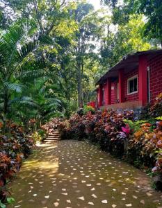 a path in front of a red house with flowers at White Water Resort dandeli in Dandeli