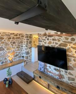 a living room with a stone wall and a tv at calm stone house elemm in Kastoria
