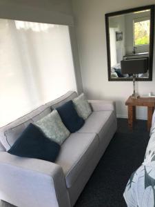 a living room with a couch with pillows and a mirror at La Casita Waiheke in Oneroa