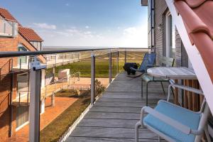 a balcony with chairs and a table and a view of the ocean at Luv in Juist