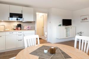 a kitchen with a table and white cabinets at Luv in Juist