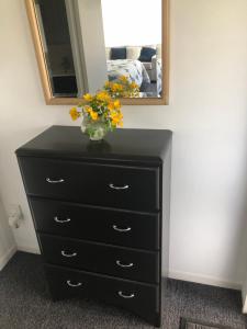 a black dresser with a vase with flowers on it at La Casita Waiheke in Oneroa
