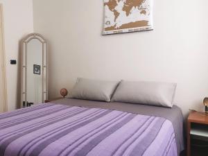 a bedroom with a bed with a purple striped blanket at B&B Le Noci in Ascoli Piceno