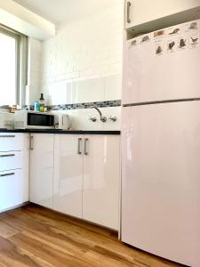 a white kitchen with white cabinets and a refrigerator at Location Location Vacation in Fremantle