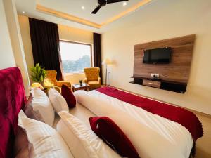 ein Hotelzimmer mit einem Bett und einem Flachbild-TV in der Unterkunft Hamshu Cafe & Stay in Kota