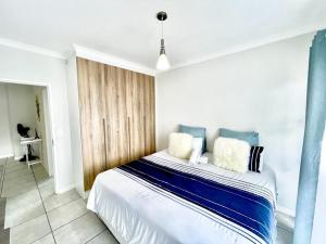 a bedroom with a large bed with blue and white pillows at TK’s Penthouse - The Blyde in Pretoria