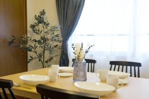a wooden table with white dishes and a vase with flowers at NHビル 4F in Tokyo