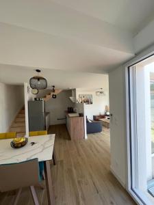 ein Wohnzimmer mit einem Tisch und einer Küche in der Unterkunft Maison 4 CH proche de la mer in Aytré