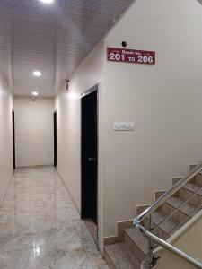 a hallway with stairs and a sign on a wall at Samraj Lodge in Akalkot