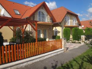 uma casa com um telhado laranja e uma cerca de madeira em Patrícia Panzió em Bük