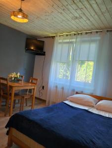 1 dormitorio con cama, mesa y ventana en Noclegi u izy en Ustrzyki Dolne