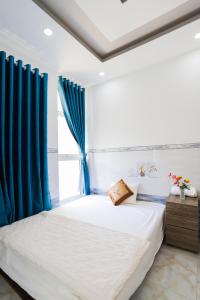 1 dormitorio con 1 cama con cortinas azules en Hotel Trâm Anh en Nhơn Trạch