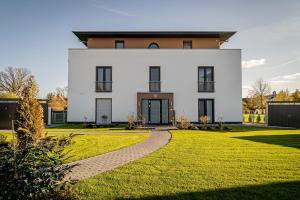a large white house with a grass yard at Luxus Spa Penthouse Royal in Göhren-Lebbin