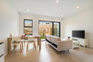 a living room with a table and chairs and a tv at Te Atatu Cozy Brand New Townhouse 5 in Auckland