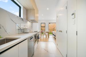 a kitchen with white cabinets and a large window at Te Atatu Cozy Brand New Townhouse 5 in Auckland +6 photos